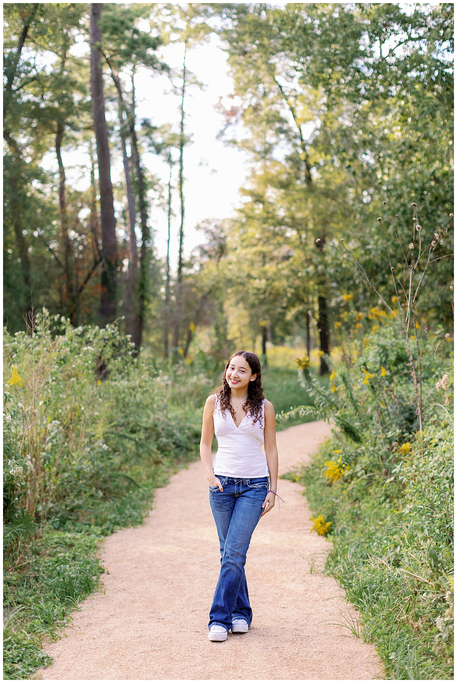 girl in jeans and white shirt walking on pathway outside Houston Arboretum
