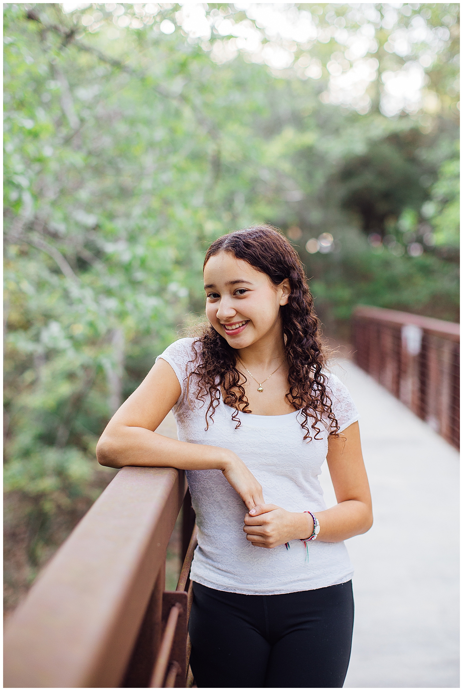 girl in white shirt and jeans leaning on bridge Houston Arboretum senior pictures