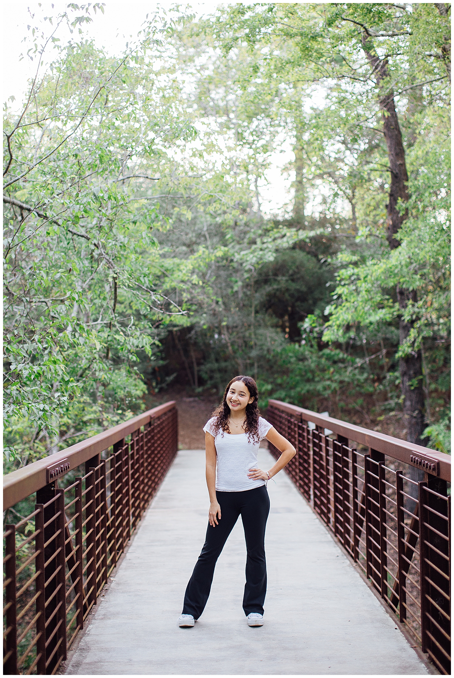 Houston senior girl in jeans and white shirt with hands in pocketsstanding on bridge at Houston Arboretum