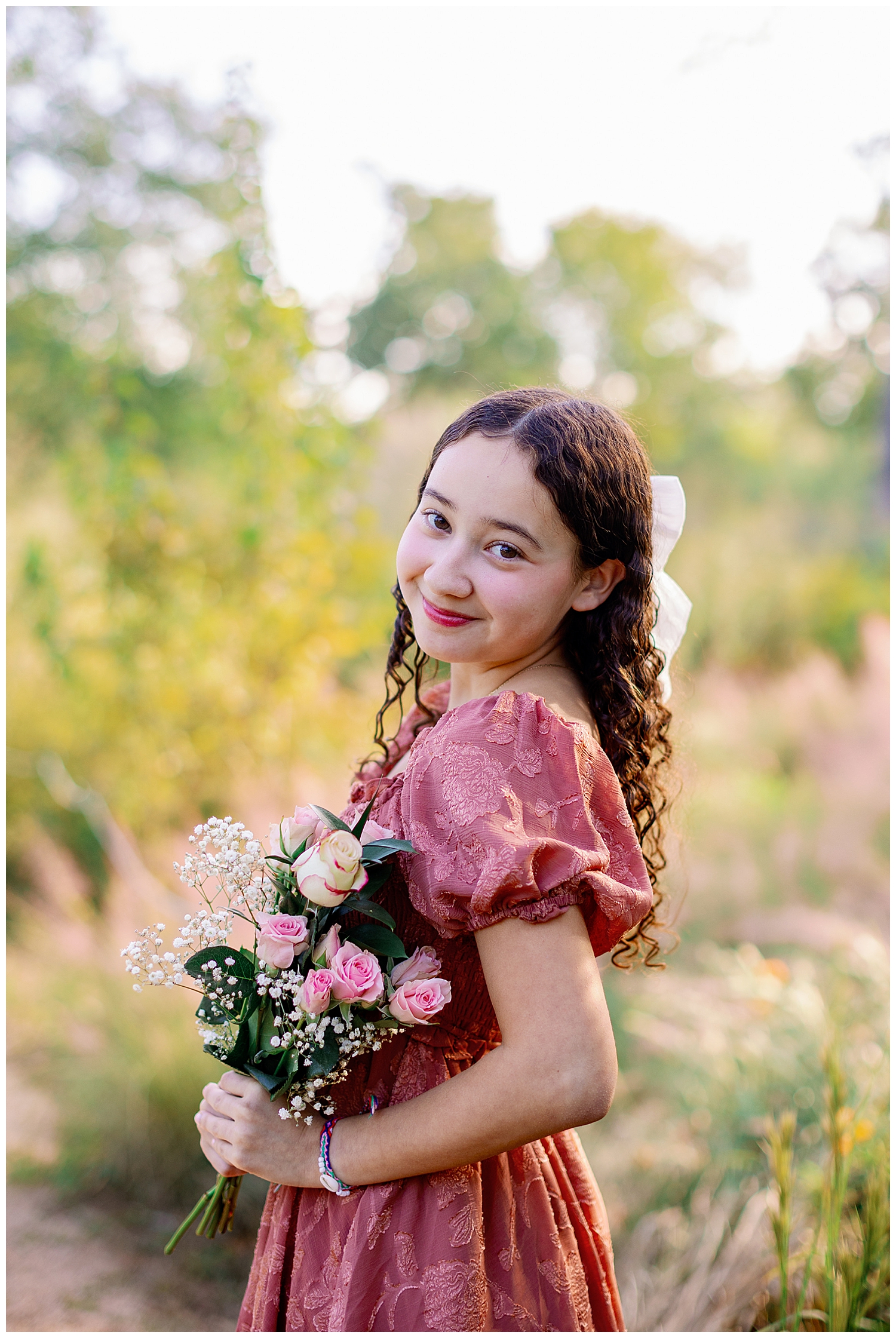 Houston senior pictures with flowers held by a girl in blush dress with white bow in hair