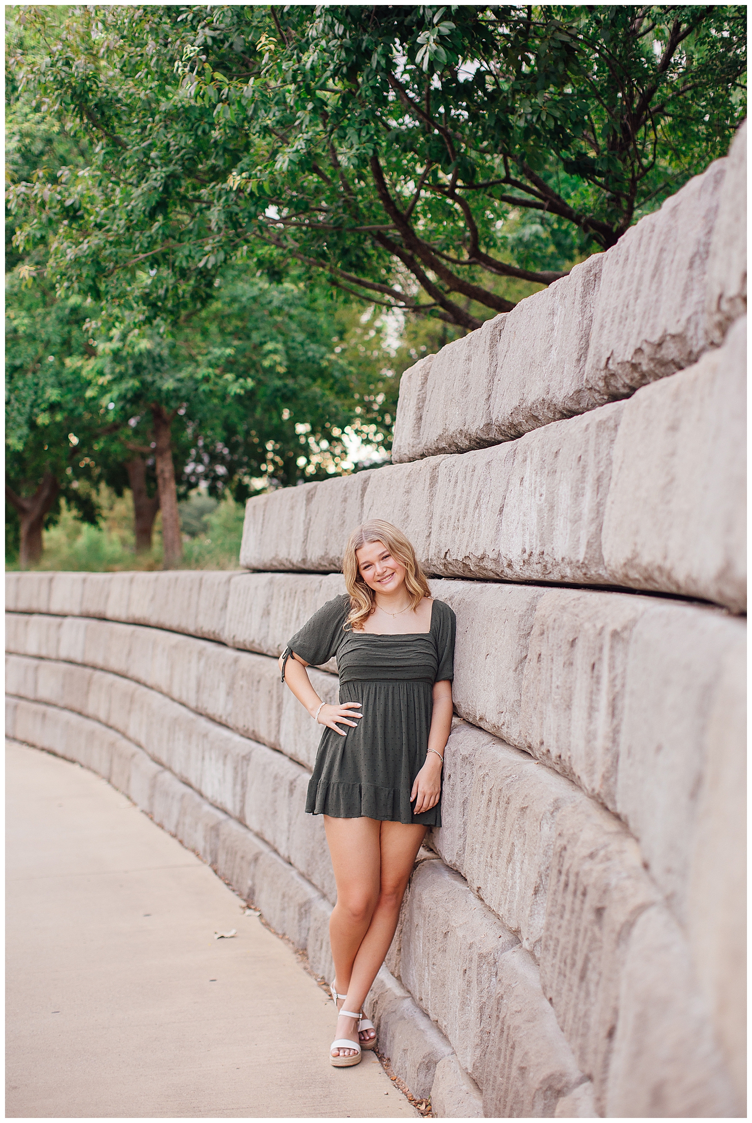 girl in army green dress leaning against gray wall for Houston skyline senior pictures downtown