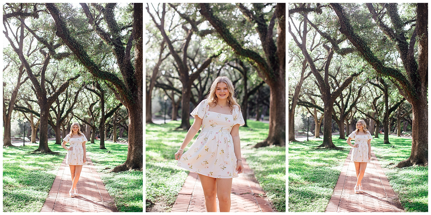 high school senior girl in white floral dress walking between trees North South Blvd. Houston