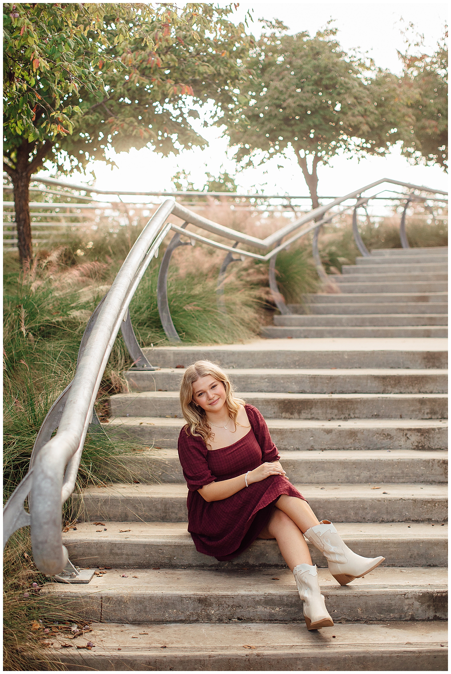 girl sitting on staircase downtown Houston in maroon dress and white boots