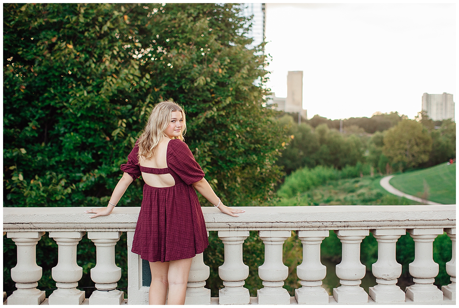 Houston skyline senior pictures with girl in maroon dress standing on Sabine Street bridge downtown