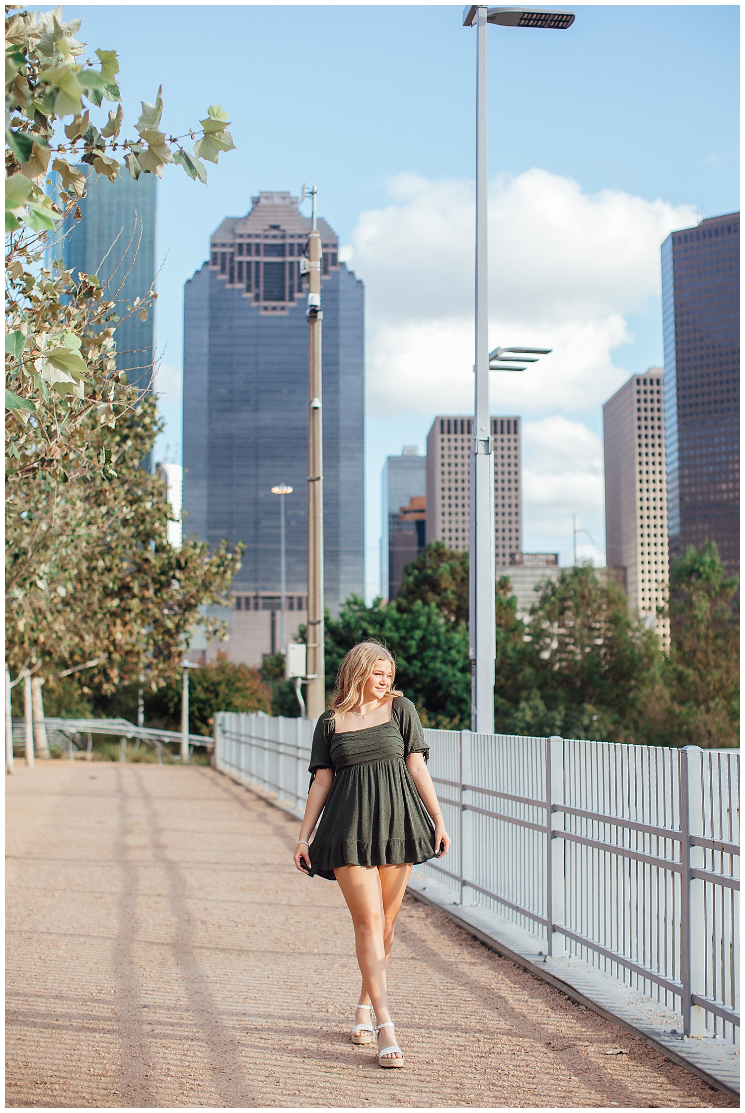 Houston skyline senior pictures with girl walking in green dress
