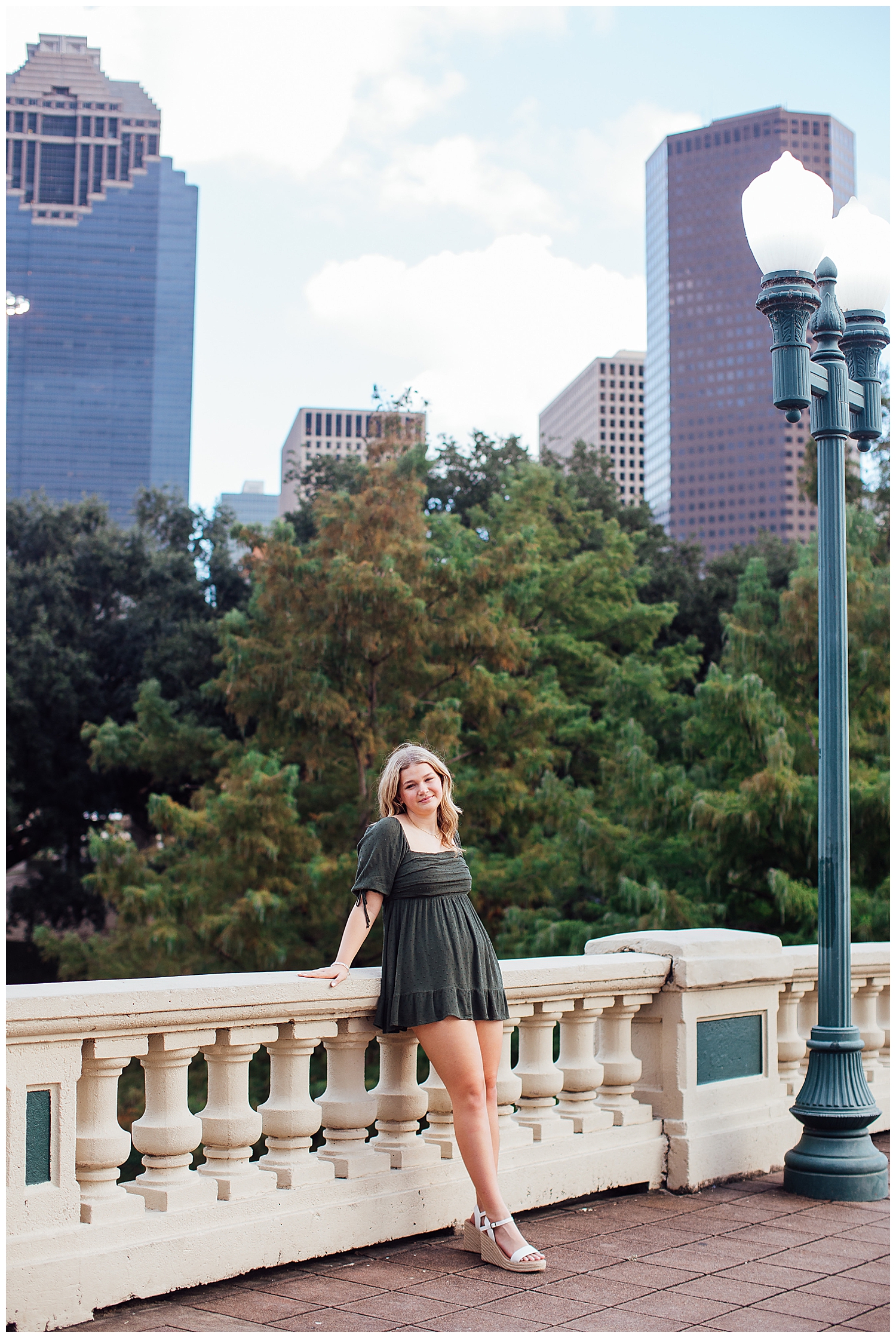 high school senior girl standing on Sabine Street bridge in front of Houston skyline in green dress