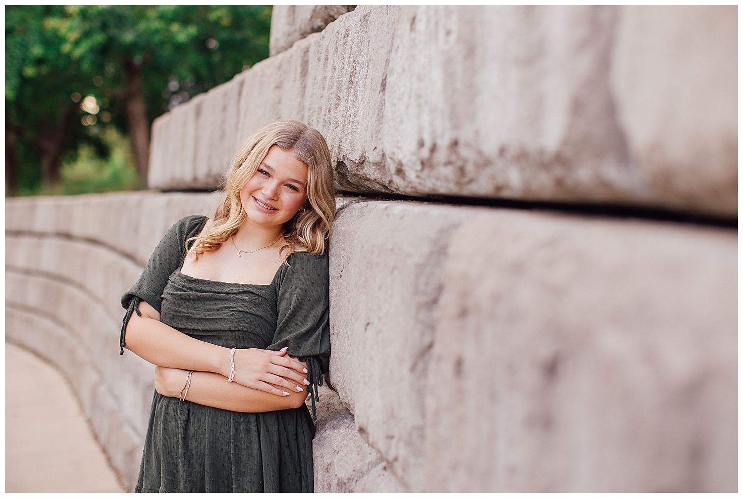 high school senior girl in green dress leaning against gray wall downtown Houston