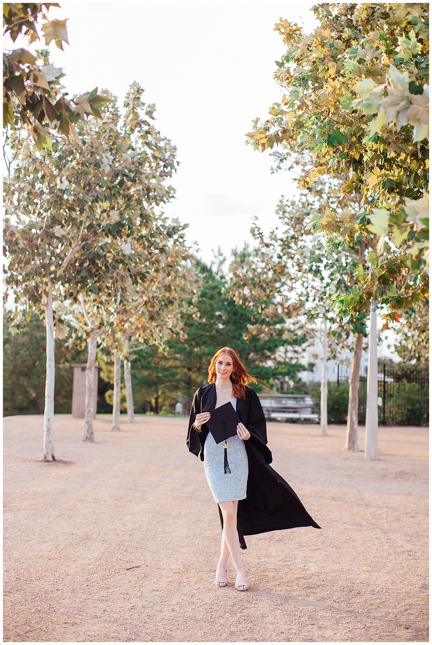 red hair girl in baby blue dress wearing black graduation gown holding cap outdoors houston downtown