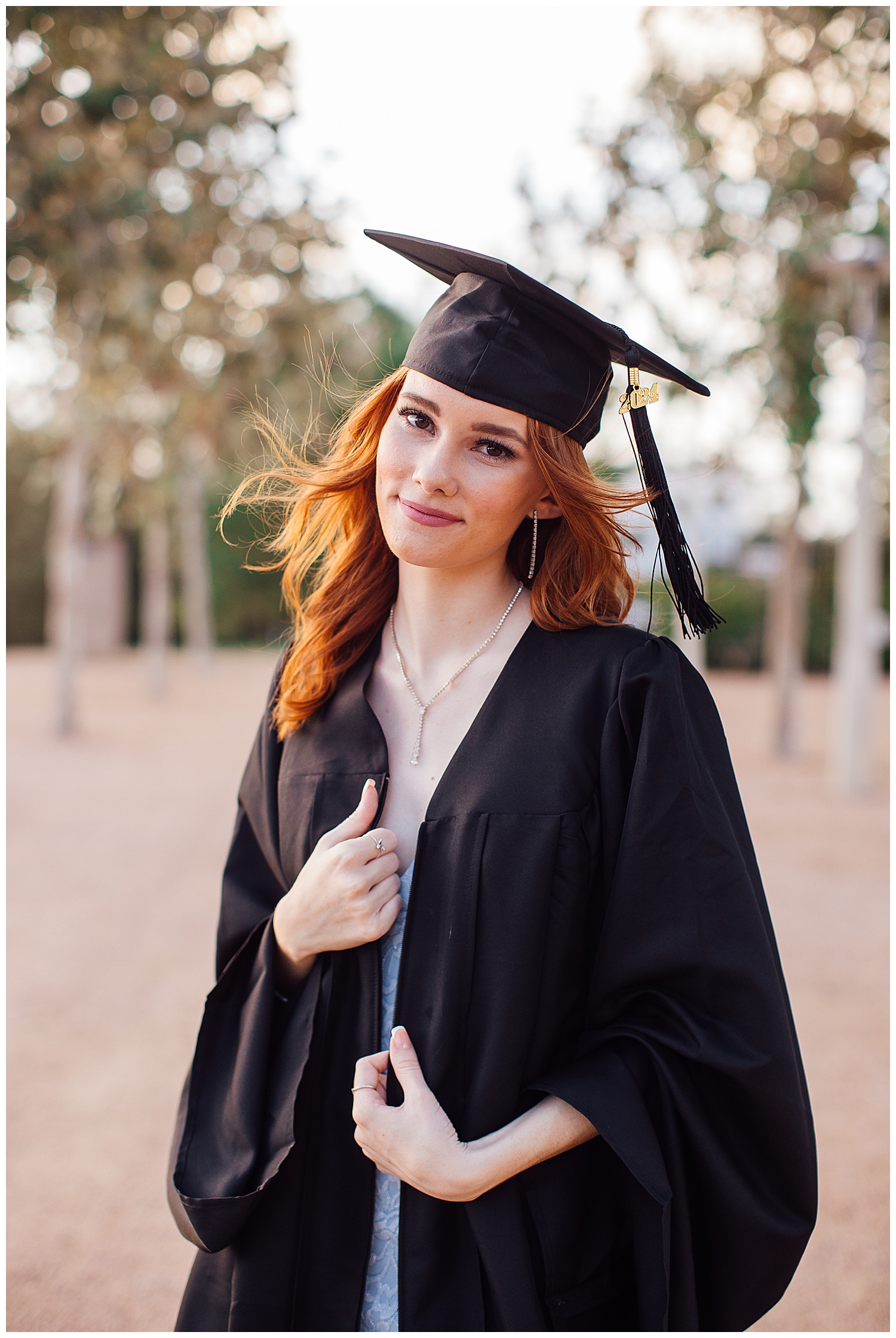 outdoor Houston senior pictures with girl in black graduation cap and gown by tree line