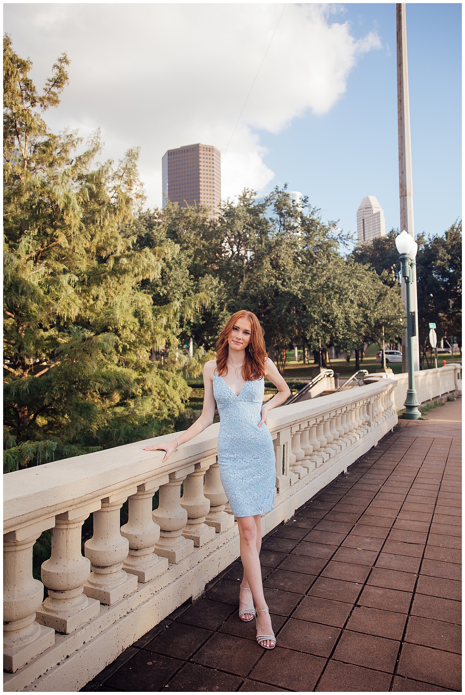 high school senior girl in blue dress standing in front of Houston skyline Sabine Street