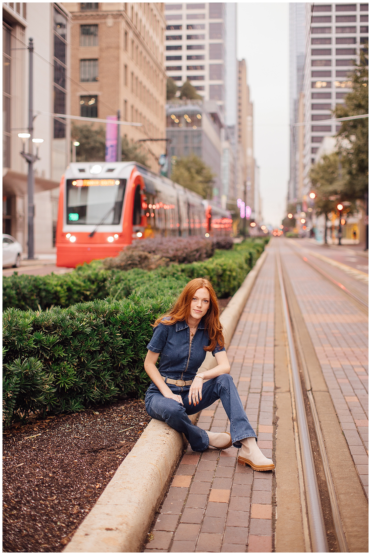 girl sitting on curb Main Street downtown Houston with METRORail in background