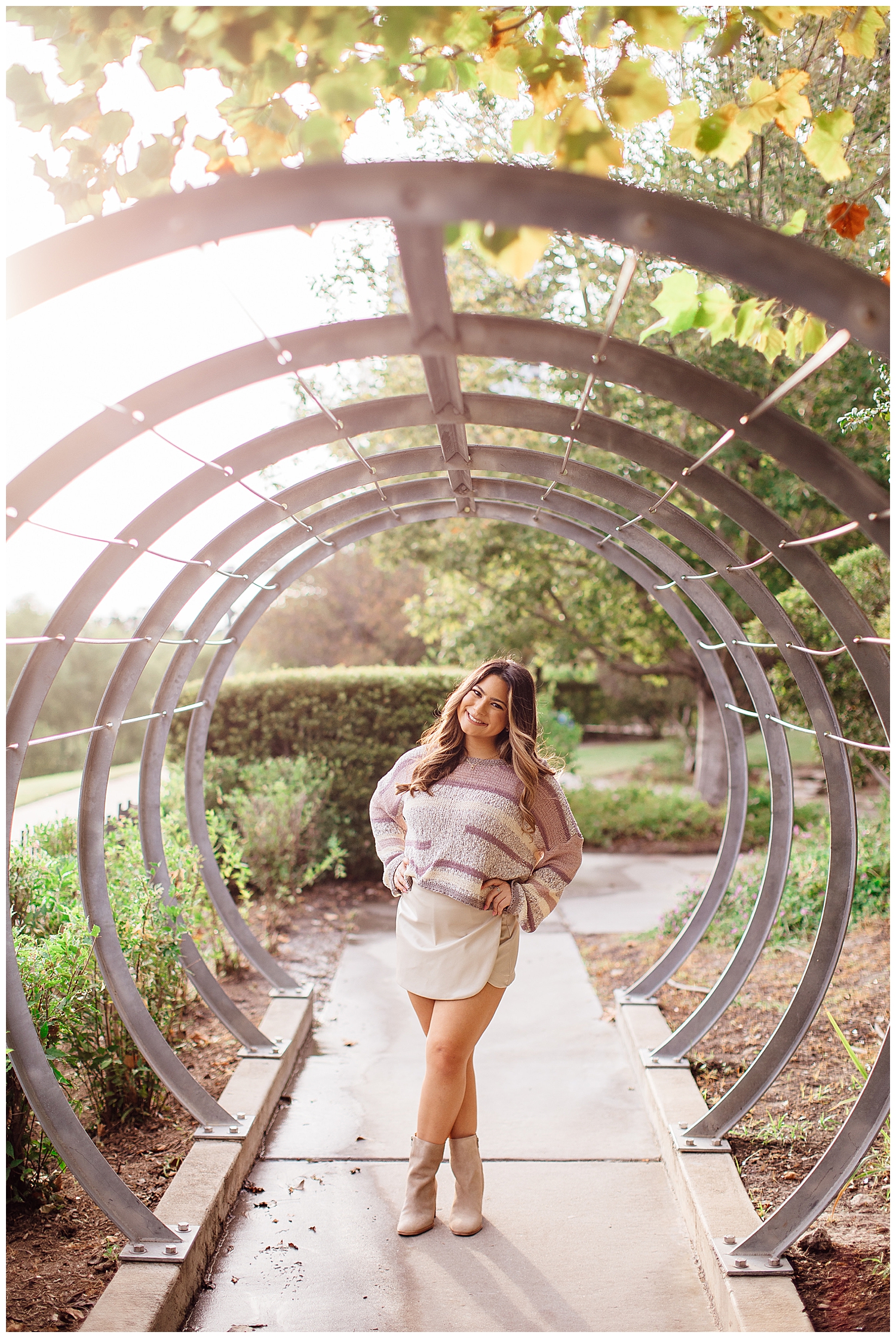 girl in white skirt and purple sweater standing under arch for Houston senior photography session downtown
