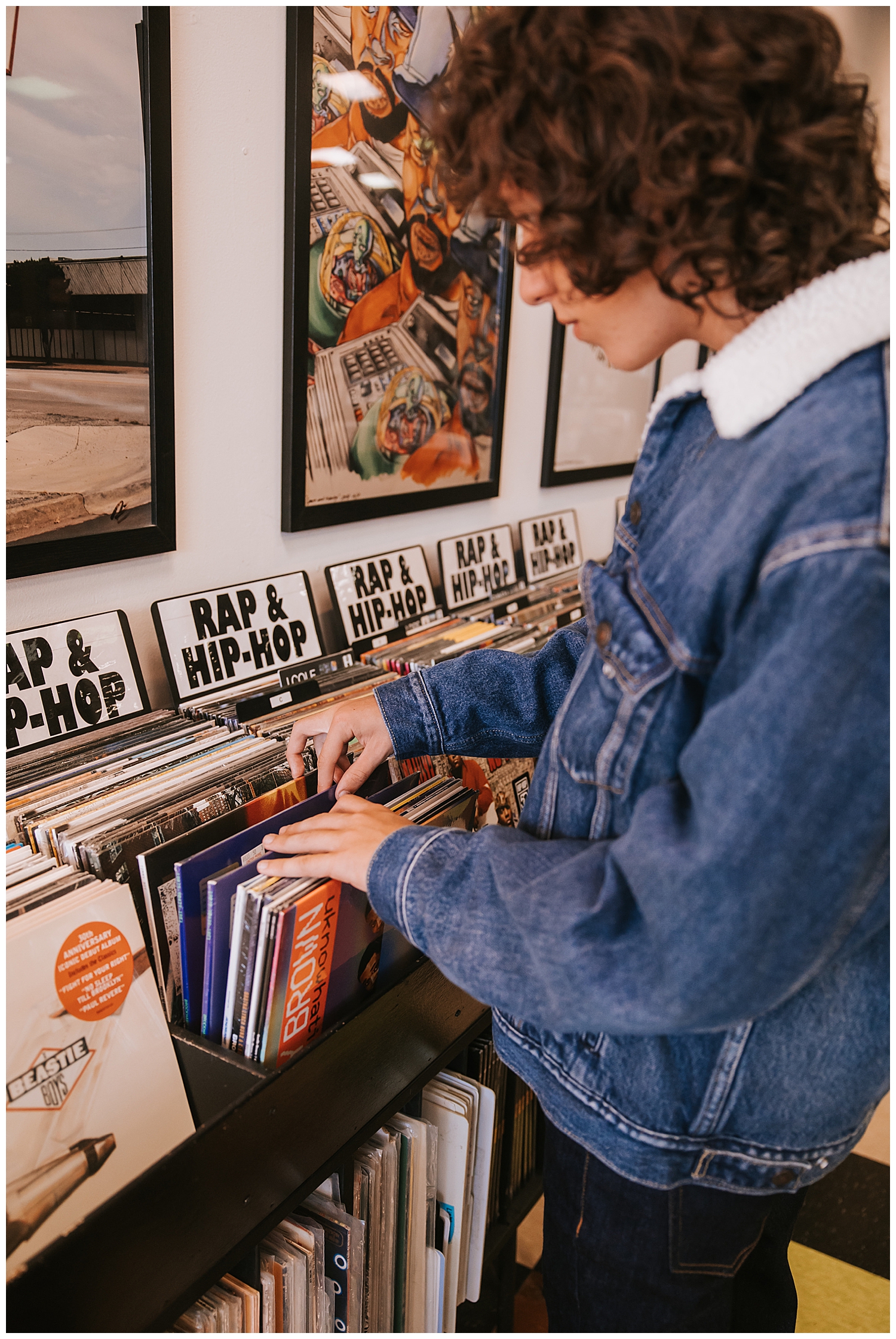 close up image of boy's hands flipping through record albums wearing denim jacket