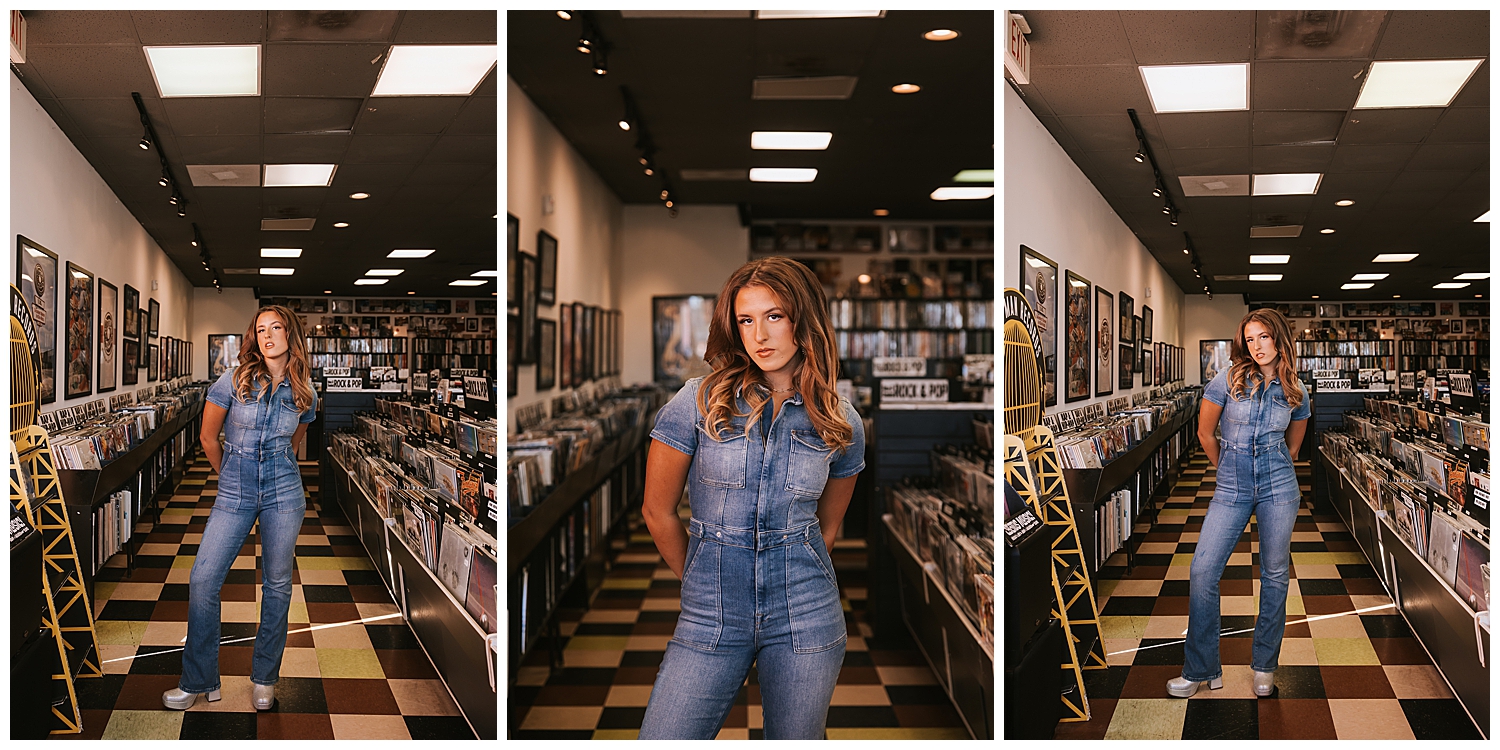 high school senior girl in denim jumpsuit standing with hands behind her back inside Cactus Record shop