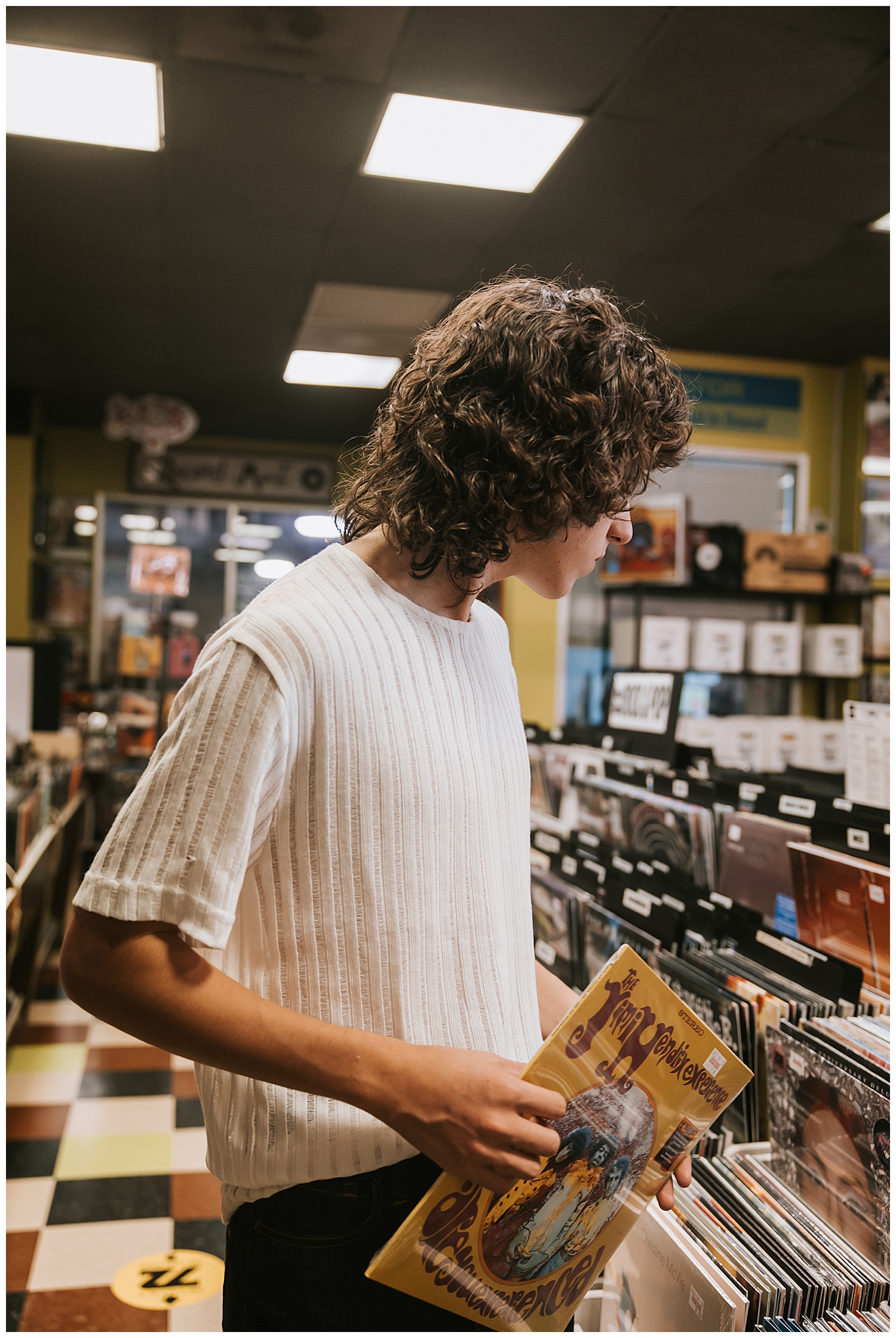 close up image of guy in white shirt looking at record albums Houston