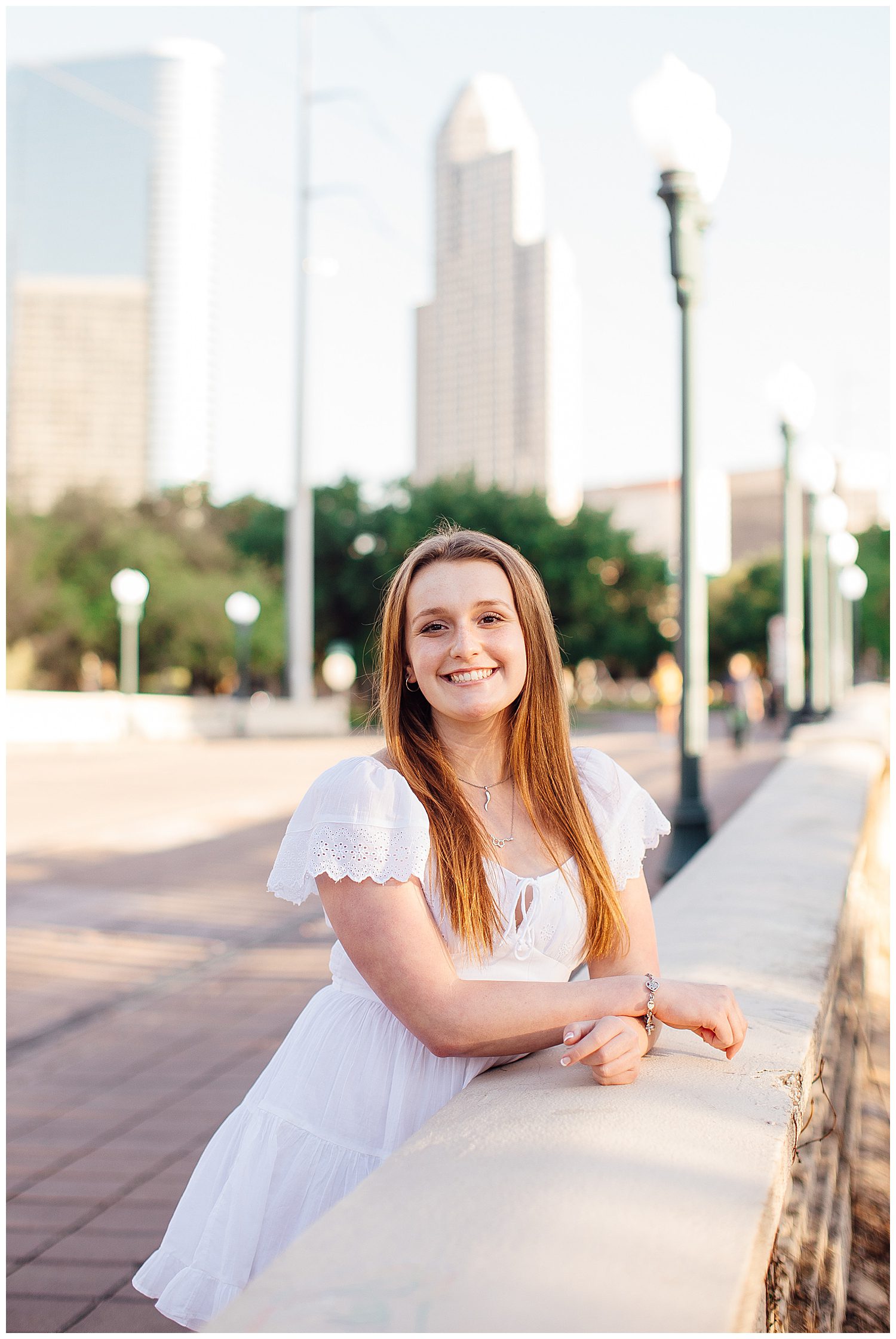 high school senior girl leaning on Sabine Street Bridge Houston in front of downtown skyline