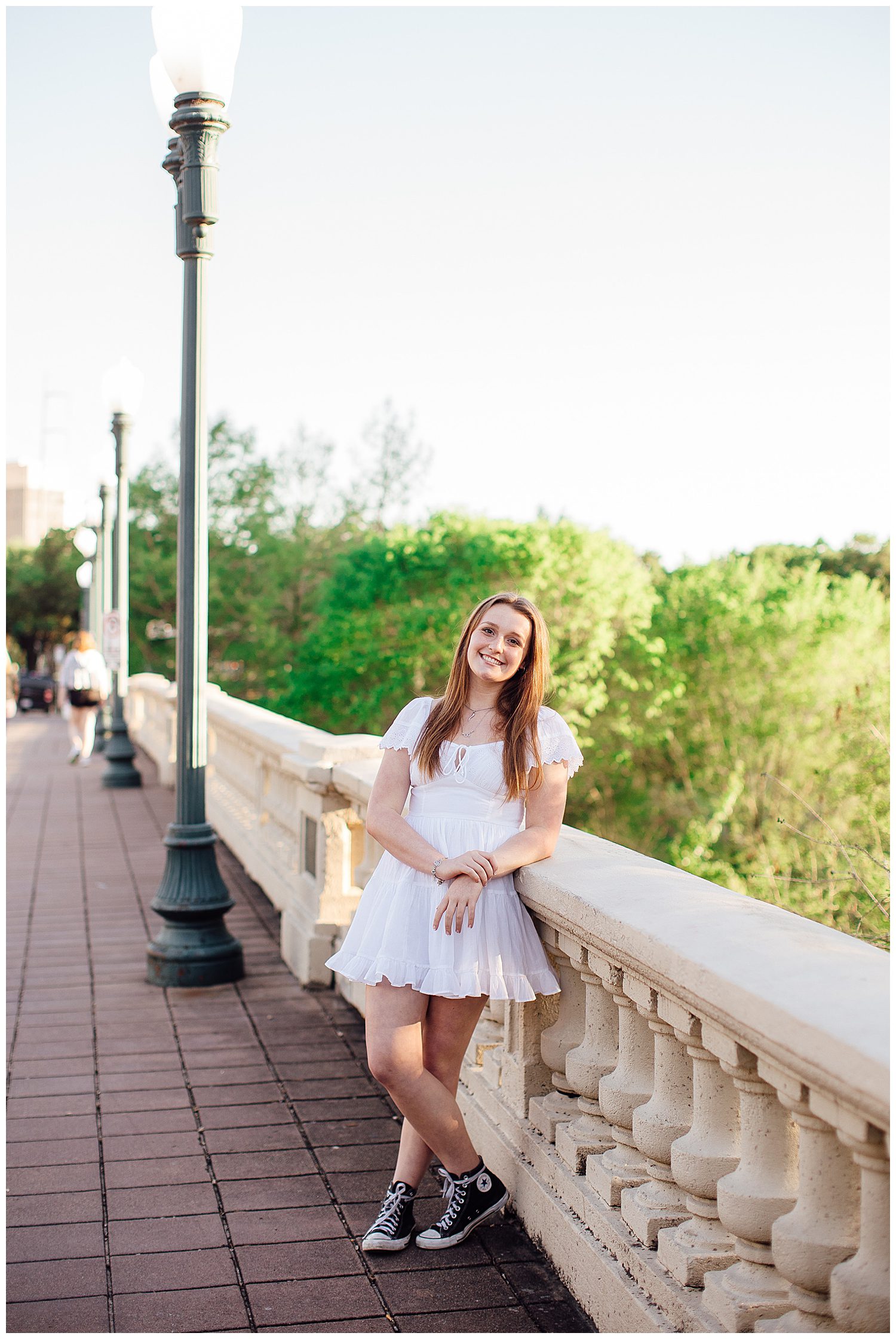 high school senior girl in white sundress leaning on Sabine Street Bridge downtown Houston