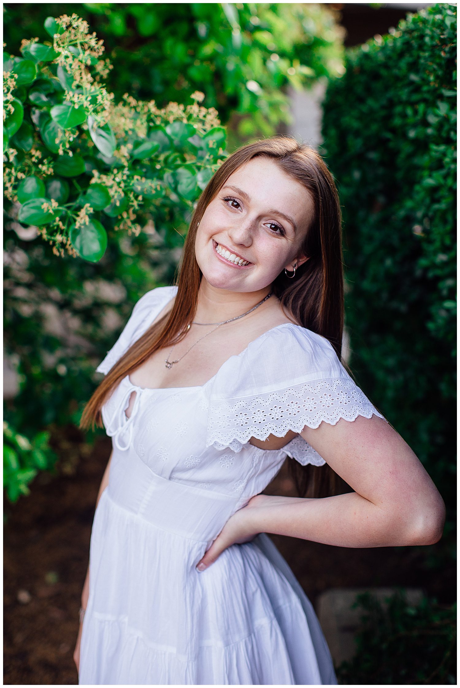 close up image of girl in white dress smiling with hand on hip posing for spring senior portraits Houston at Sabine Park