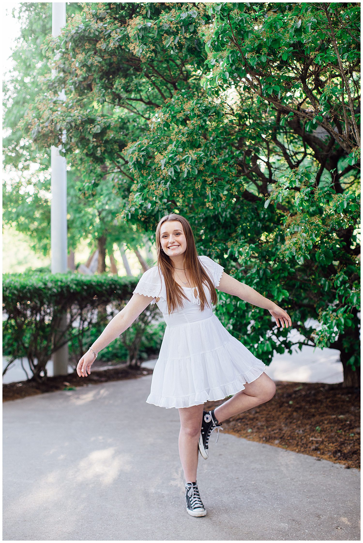 girl in white sundress twirling outdoors for Spring Senior Portraits Houston downtown