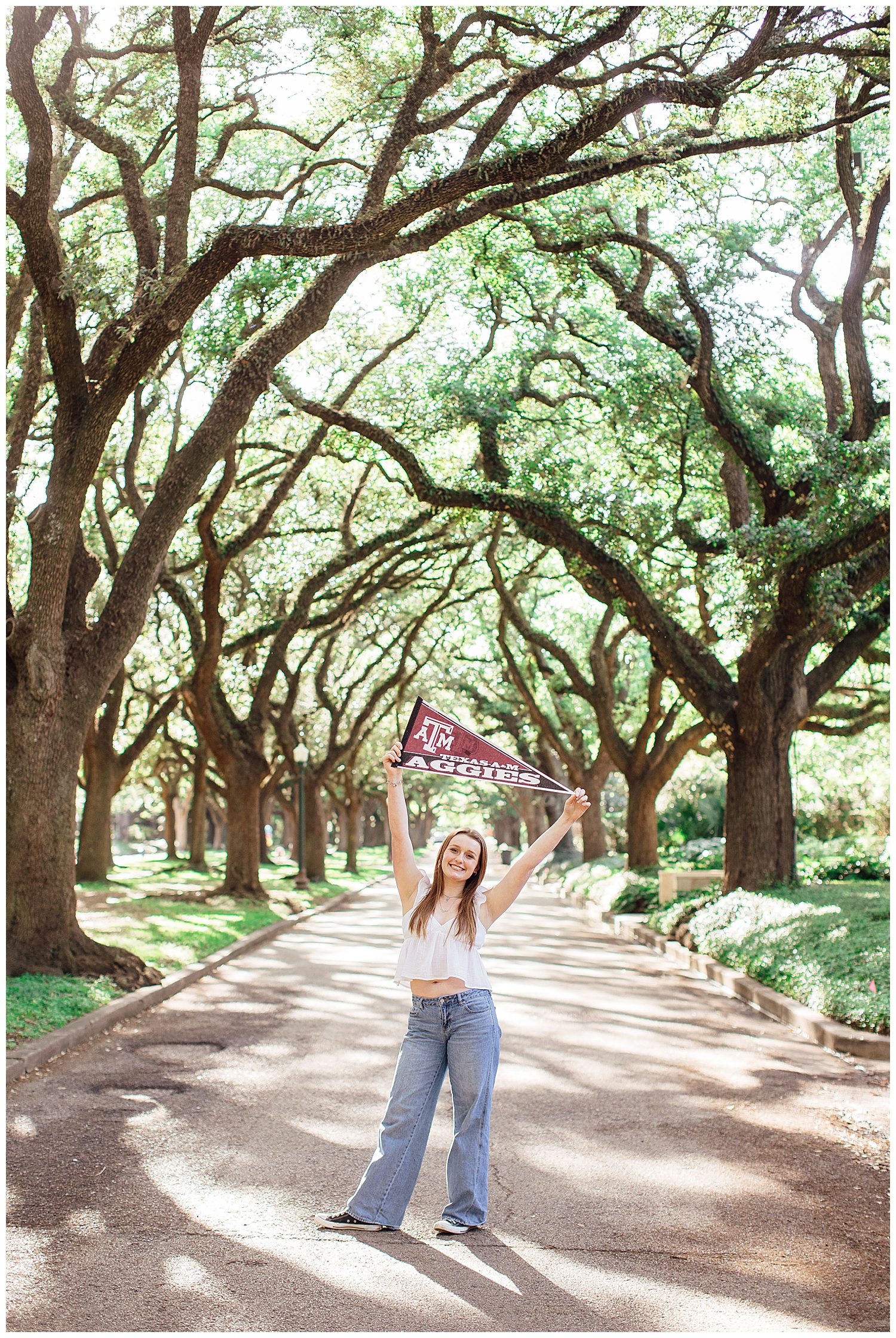 high school senior girl standing in tree line Houston holding Aggie sign above her head