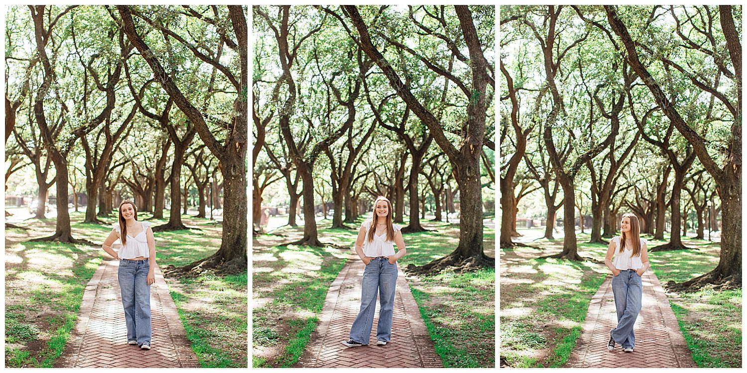 high school senior girl wearing jeans and white shirt standing outdoors under trees for spring senior portraits Houston. Texas