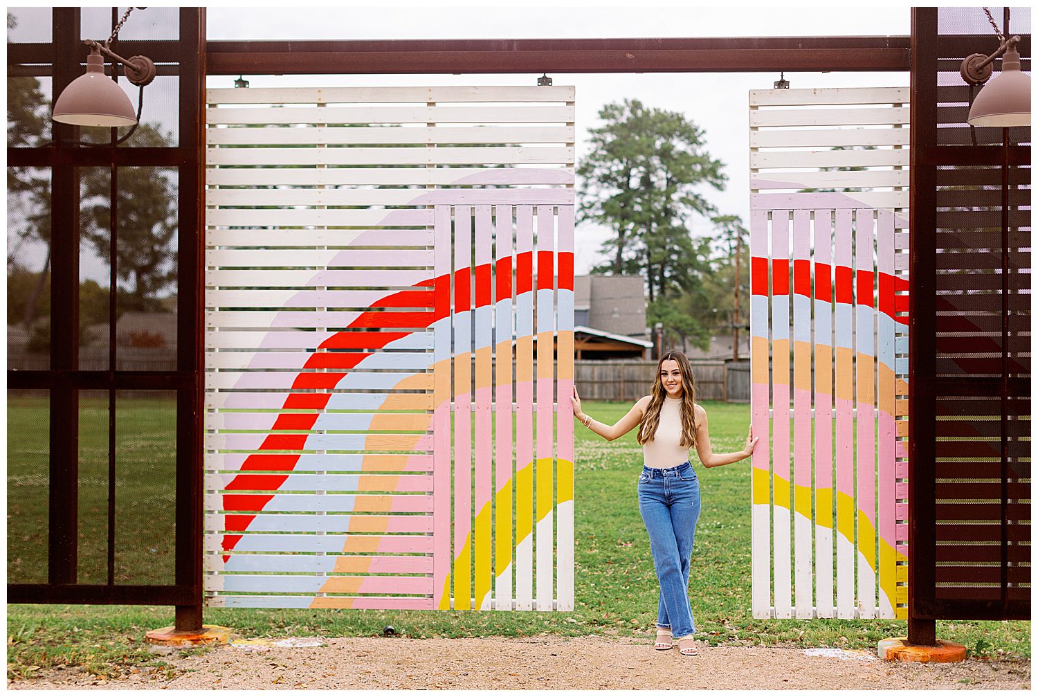 high school senior girl in jeans and beige top standing between rainbow walls Houston