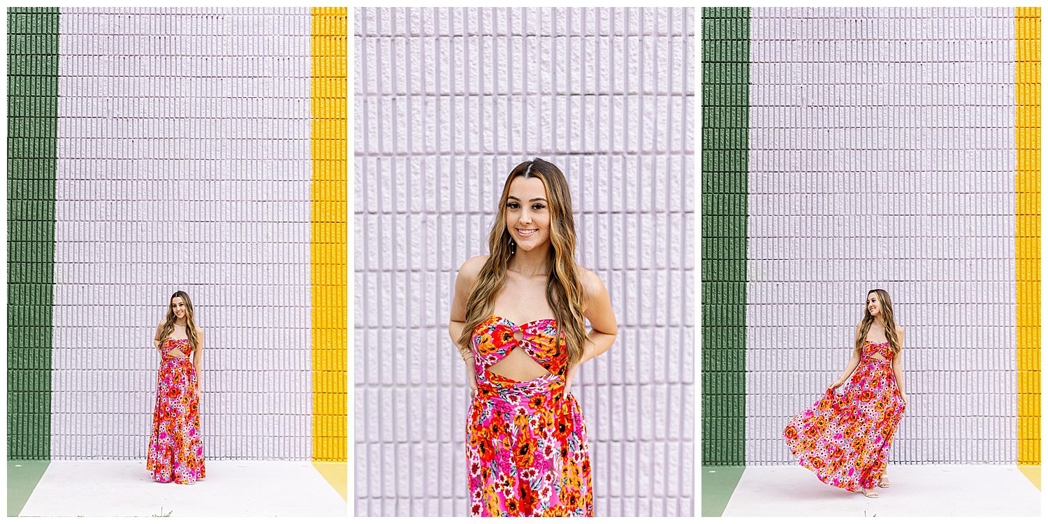 high school senior in red floral sundress posing with hands behind her back for sugar and cloth color wall portraits in Houston, Texas