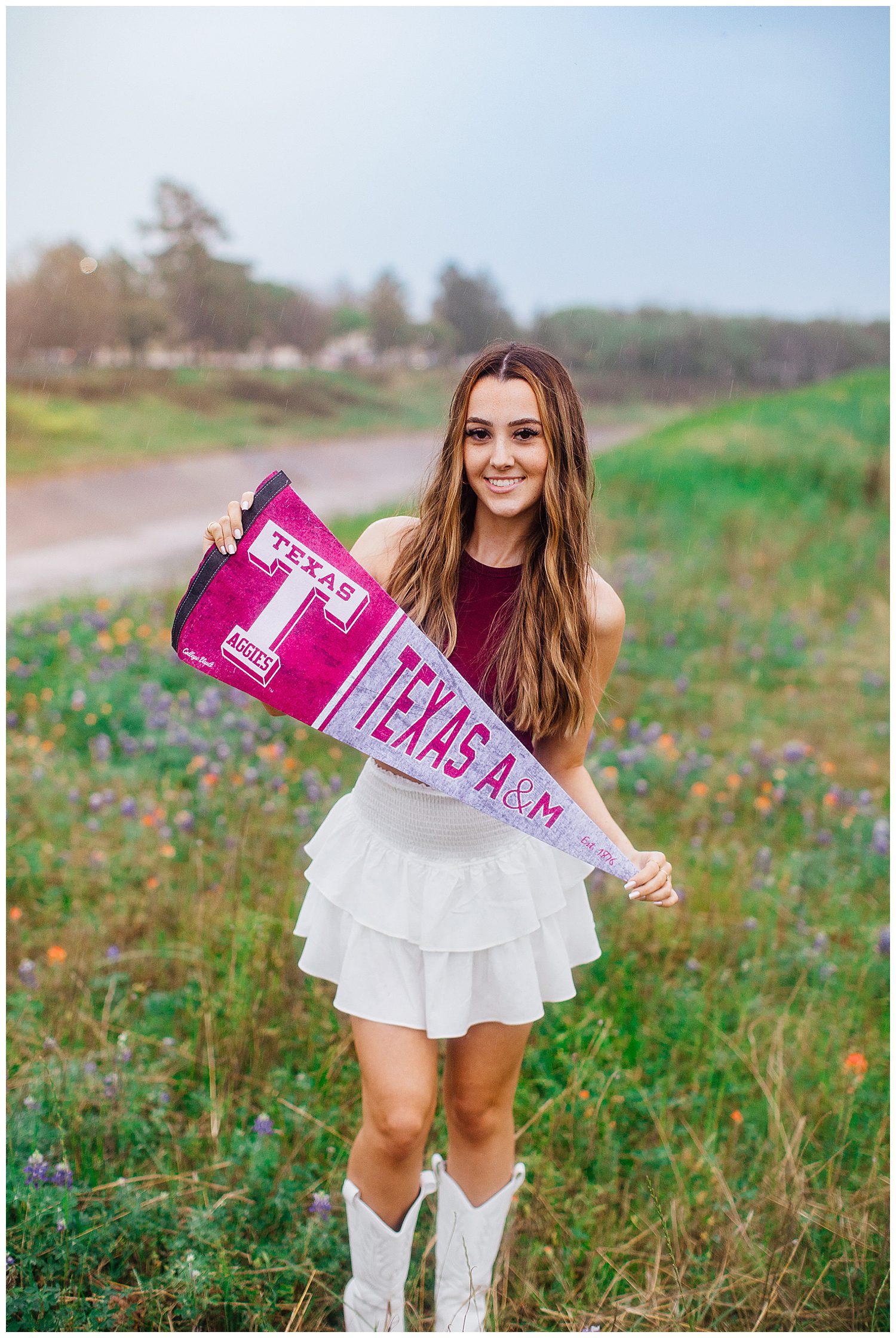 high school senior girl standing in bluebonnet field holding Aggie sign